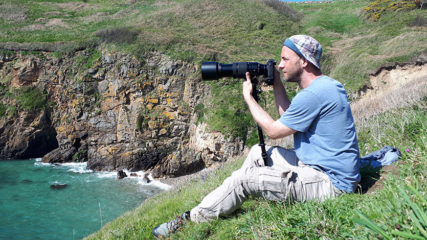 Dan sat on a cliff in Herm with camera